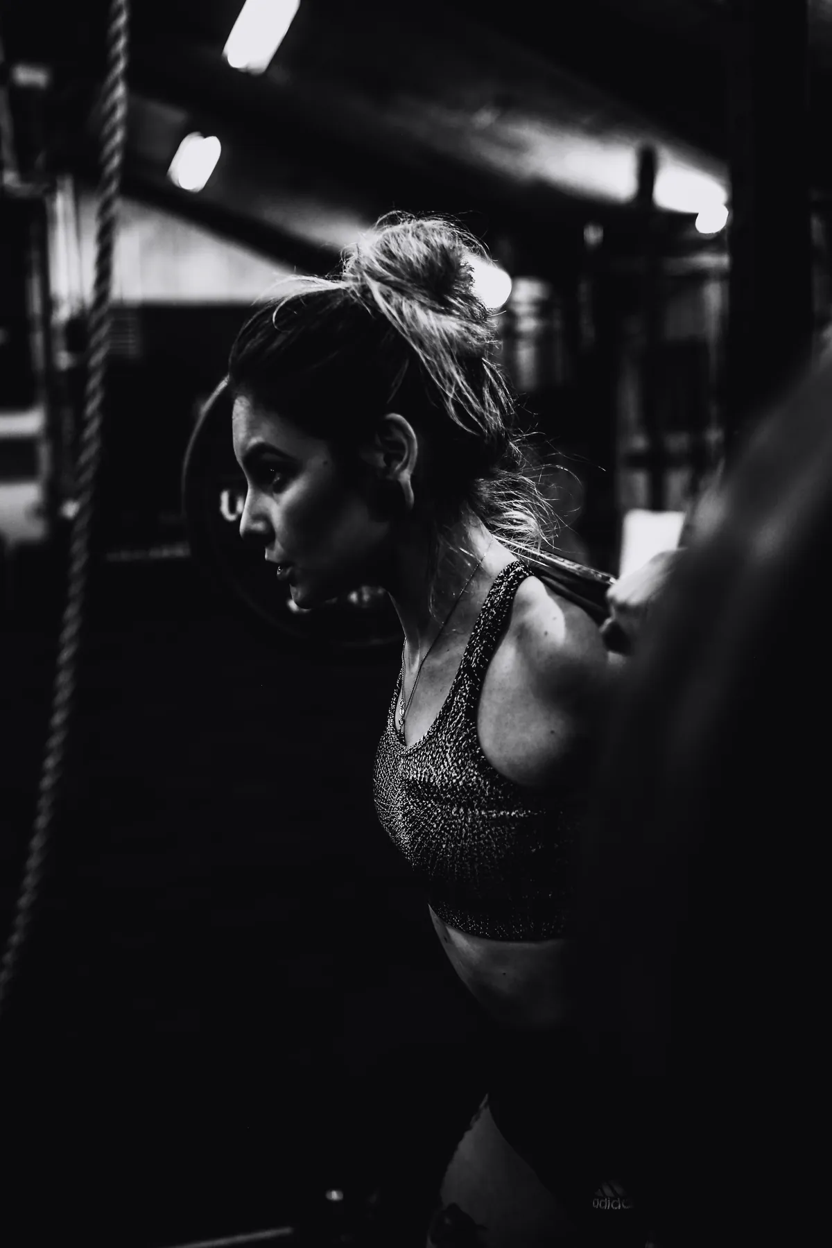 An athlete settling under a loaded barbell in a dark gym.